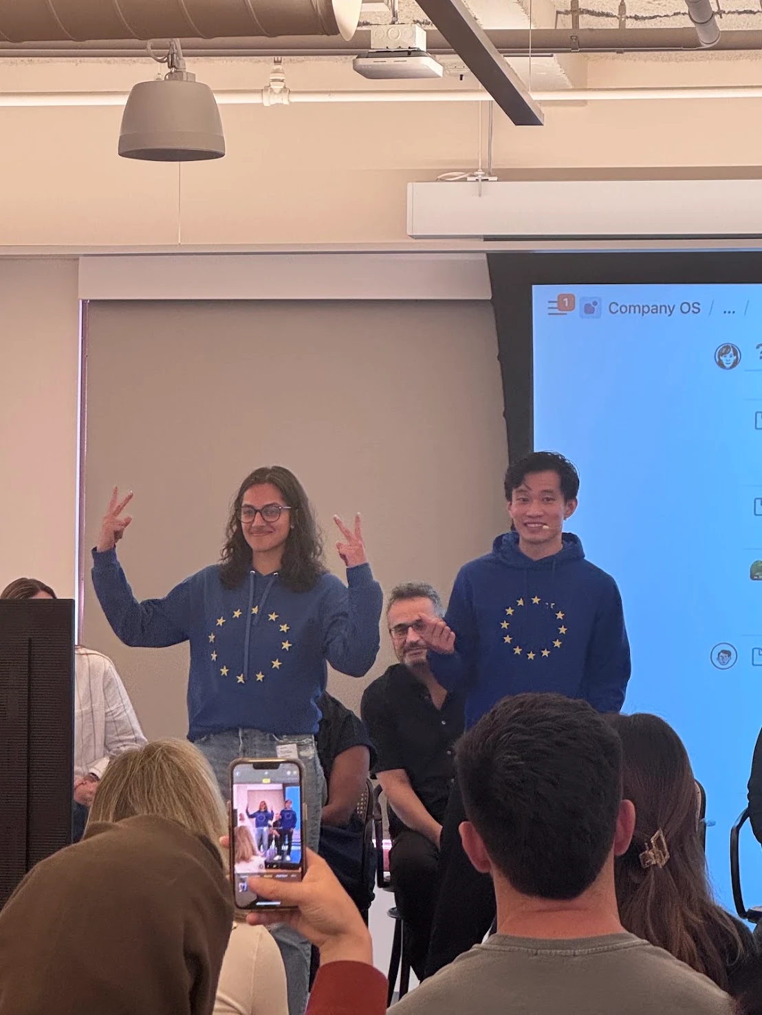 Saatchi in a blue hoodie presenting to a seated audience at Notion, alongside CEO Ivan Zhao