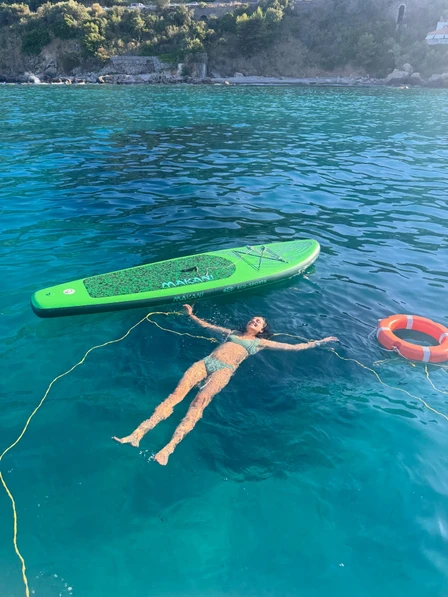 Saatchi Bhalla floating in the sea beside a paddleboard